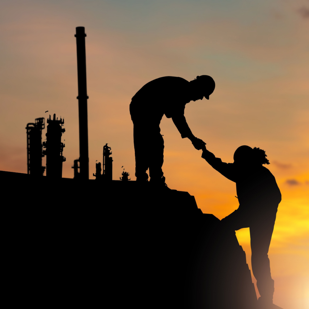 Silhouettes of Two workers helping each other up a hill with factory background, Engineer team people helping each other friend at Sunset Manufacturing Refinery Plant